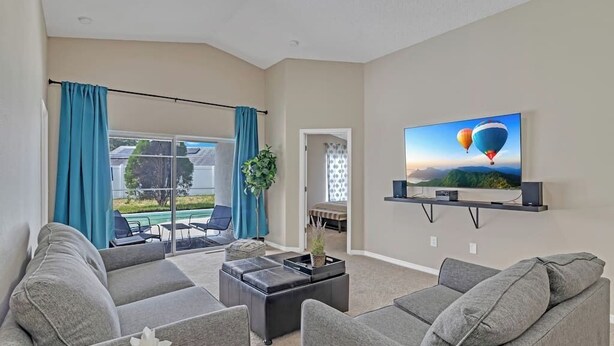Ein Wohnzimmer mit grauen Sofas, einem Couchtisch und einem Fernseher an einem Wandregal.
