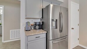 Eine Küche mit Edelstahlkühlschrank, Kaffeemaschine und Mikrowelle auf der Arbeitsfläche.