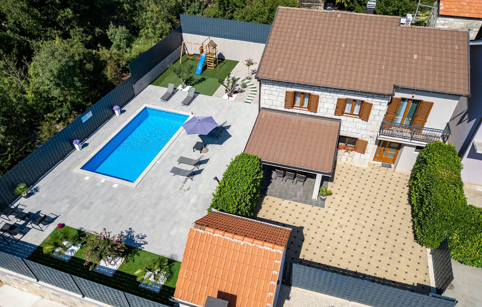 Vue aérienne d’une propriété dotée d’une piscine, d’un espace salon extérieur et d’un jardin.