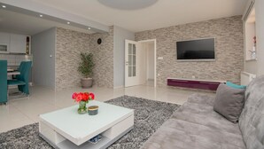 Un salon moderne avec un canapé, une table basse et un téléviseur fixé au mur.