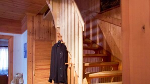 A wooden staircase with a coat hanging on the wall.