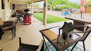 An outdoor patio with wicker furniture, a ceiling fan, and a view of the backyard.