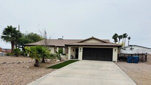 A single-story house with a tiled roof, a concrete driveway, and a garage.