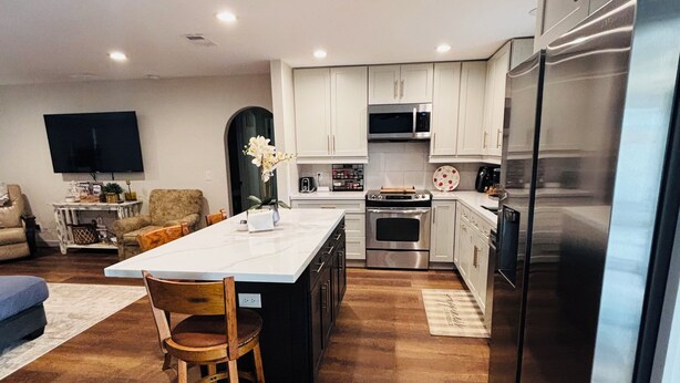 A modern kitchen with white cabinets, a stainless steel refrigerator, and a central island with seating.
