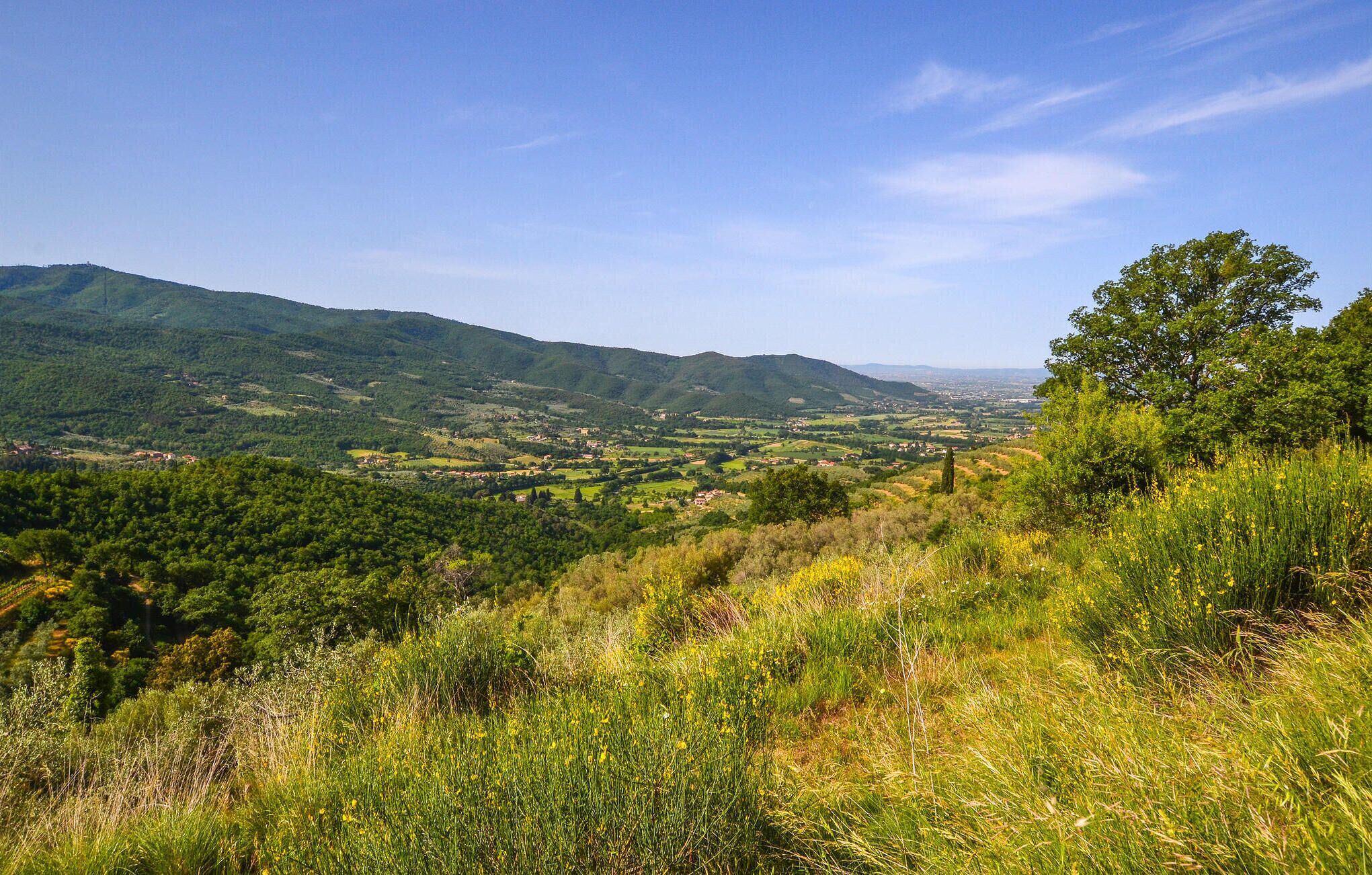 A mountainous landscape with a valley and scattered buildings.