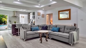 A modern living room with a grey sectional sofa, a round coffee table, and a large mirror on the wall.