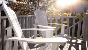 Una sedia Adirondack bianca su un pontile di legno con ringhiera.