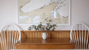Un tavolo di legno con un vaso bianco e piante verdi, affiancato da due sedie bianche, di fronte a una parete con una grande mappa.