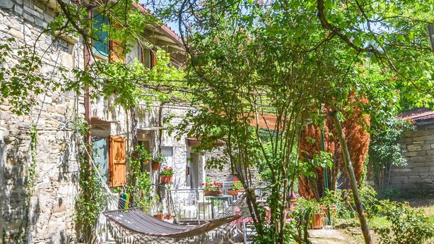 Un cortile con edifici in pietra, un'amaca e piante in vaso.