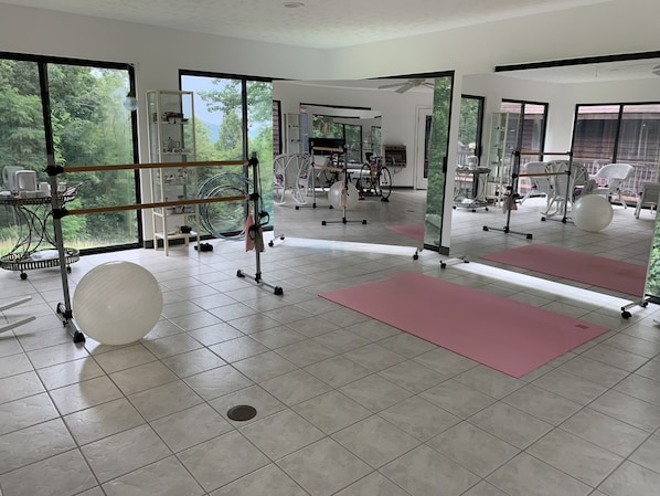 A spacious gym with exercise equipment, large windows, and a tiled floor.
