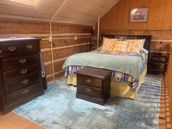 Una habitación de madera con una cama, un aparador y una mesita de noche.