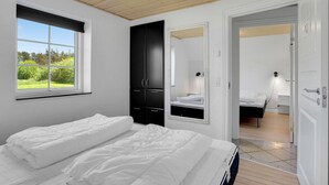Un dormitorio con una cama grande, un armario, un espejo y un baño visible a través de una puerta abierta.