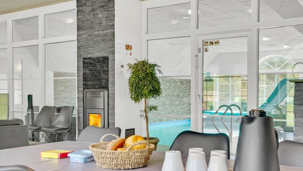 Un espacio interior moderno con chimenea, zona de estar y vistas a una piscina exterior.
