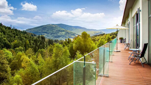 A balcony with a glass railing overlooking a mountainous landscape.