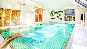 An indoor swimming pool with a patterned floor, white walls, and a large window.