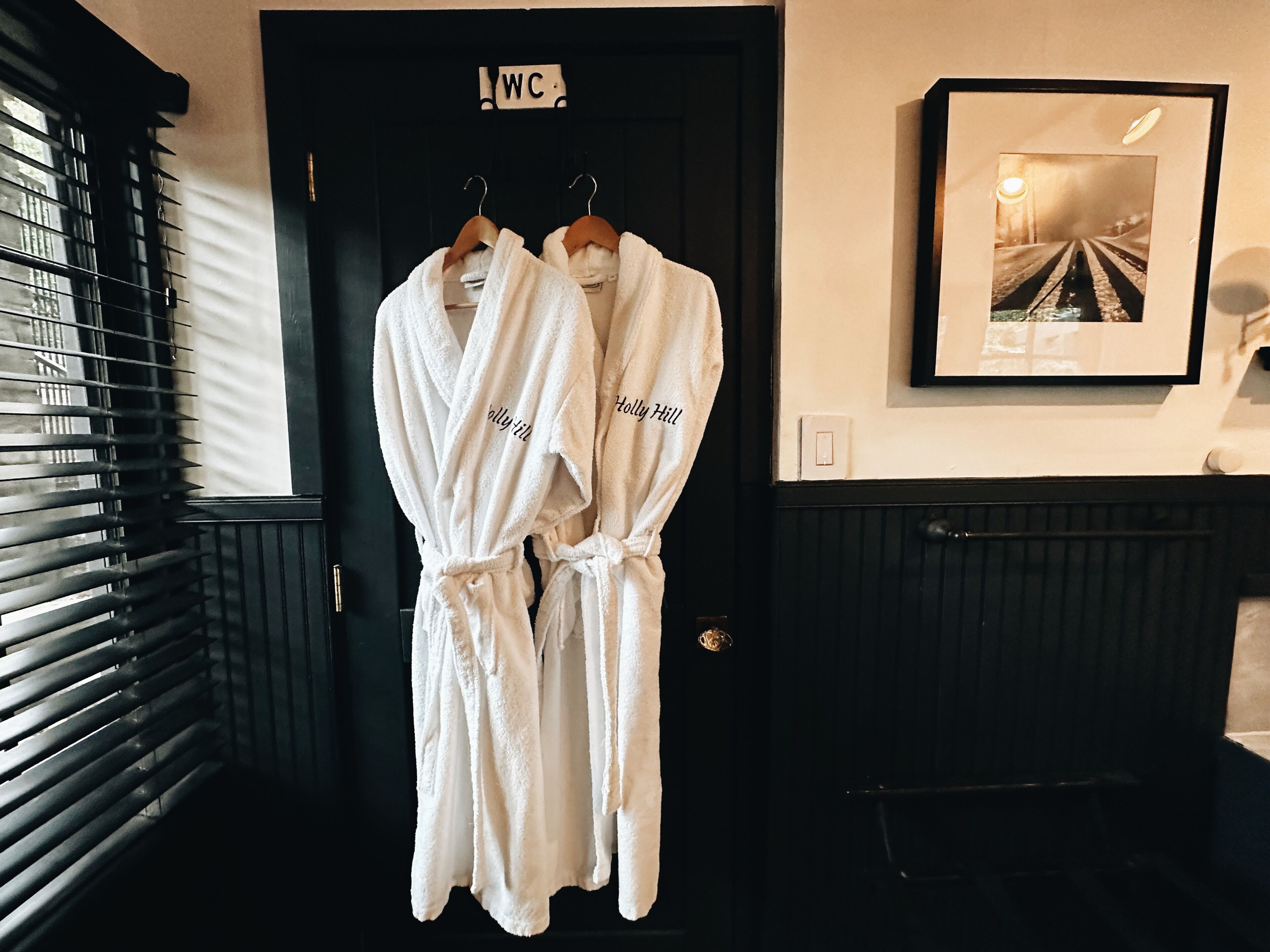 Deux peignoirs blancs sont accrochés à une porte sur laquelle est apposée une pancarte indiquant les toilettes.