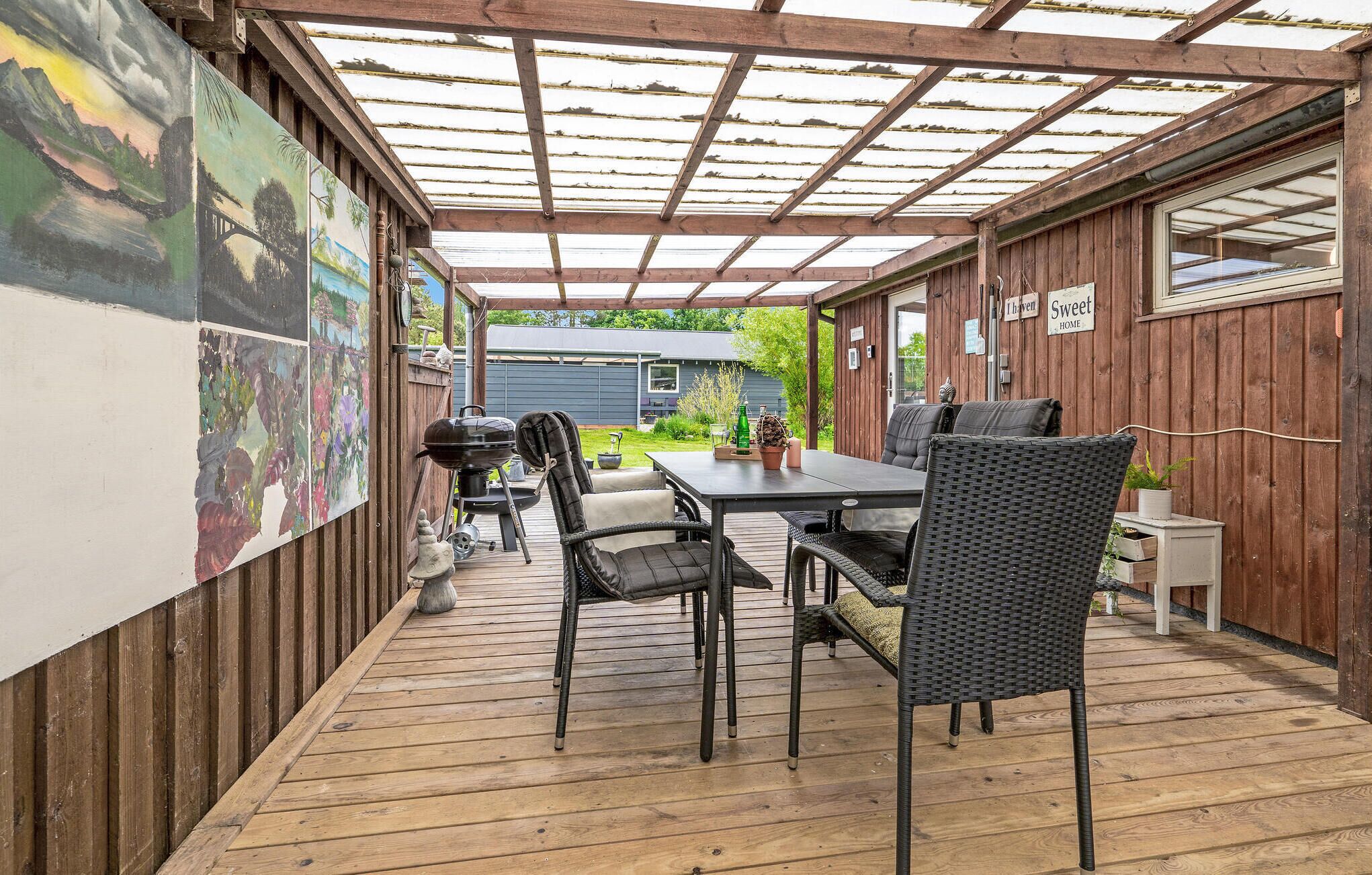 Une terrasse couverte avec une table et des chaises, un barbecue et une plateforme en bois.