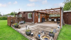 A wooden house with a covered patio, outdoor seating, and a fire pit. - 2 bedroom nice home in Vordingborg (Vordingborg)