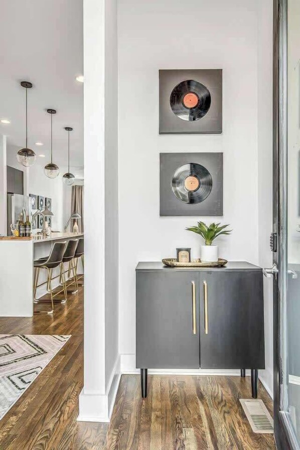 A modern kitchen with a central island, pendant lighting, and a dark-colored cabinet with gold handles.