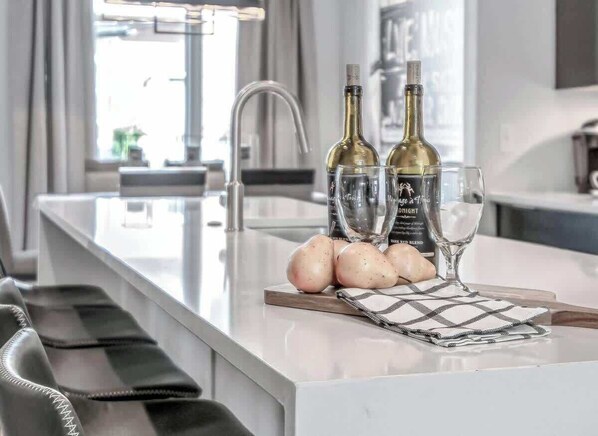 Una cocina moderna con una isla central, dos botellas de vino y copas.