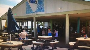 An outdoor seating area with tables and chairs, a covered section, and a sail with text. - Myrtle Beach Resort Unit 6201 - Ocean Getaway (Myrtle Beach)