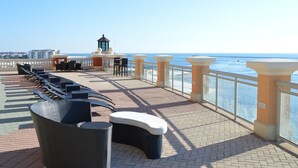 Eine Strandterrasse mit Liegestühlen, einer kleinen Bar und Blick auf das Meer.