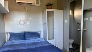 A bedroom with a bed, a wardrobe, and a bathroom. - Kur Cow Farmstay (Kuranda)