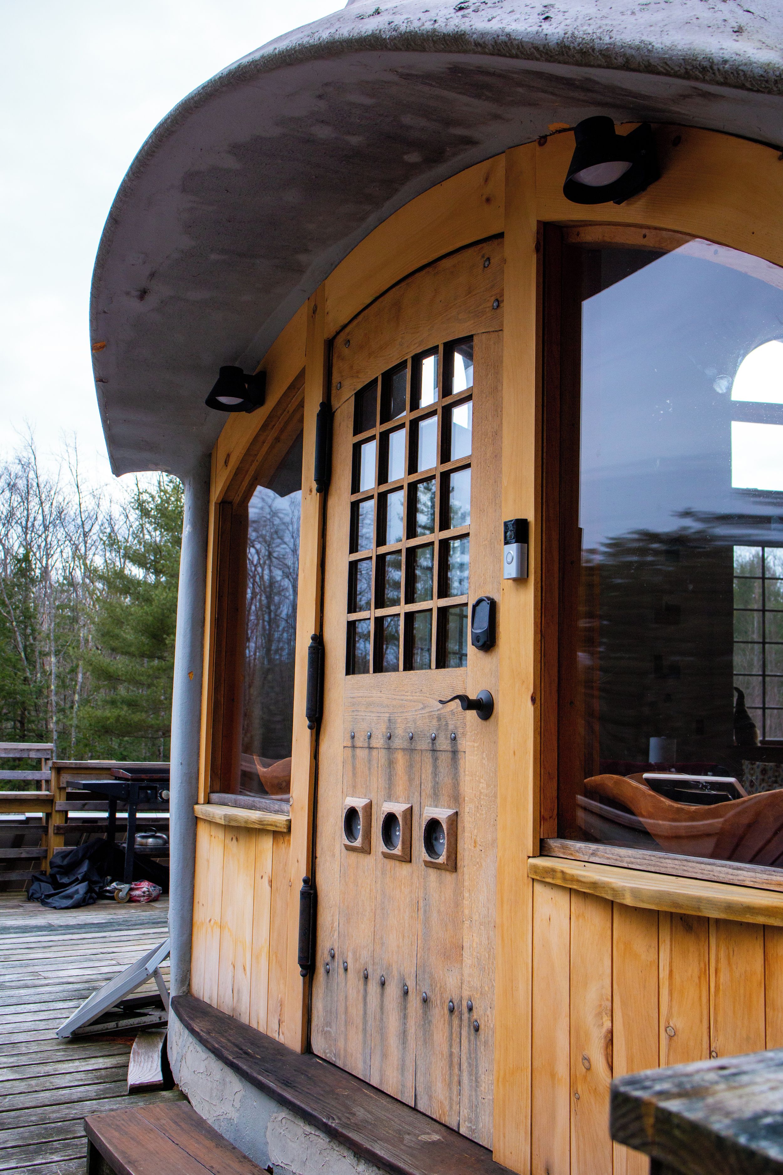 A wooden cabin with a large window, a door with a grid pattern, and a bench outside.