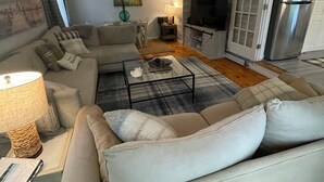 Un salon comprenant un canapé, une table basse, un téléviseur et un réfrigérateur.
