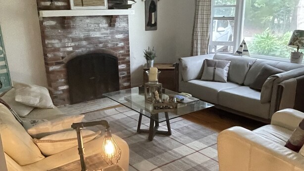 Un salon chaleureux avec une cheminée, un canapé, une table basse et une petite table en bois.
