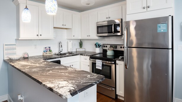 A modern kitchen with white cabinets, stainless steel appliances, and a marble countertop. - 300ft to the Beach • Central A/C, Linens & Towels, Beach Badges & Gear Included (Seaside Heights)
