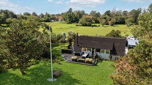 A modern house with a sloped roof, surrounded by a well-maintained lawn and trees. - Cozy home in Gørlev with house sea view (Gørlev)