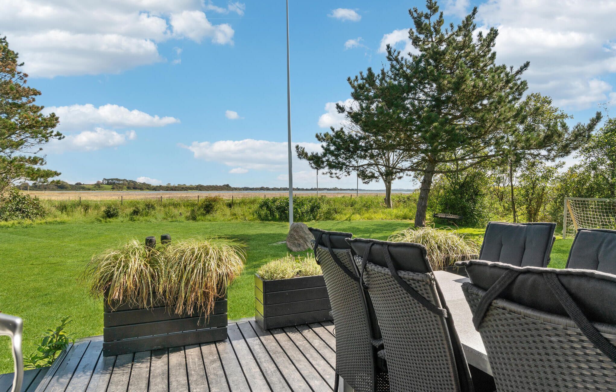 Une terrasse avec des sièges extérieurs, une vue sur un champ verdoyant et un arbre.
