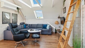 A modern living room with a grey sectional sofa, black leather chairs, a round coffee table, and a wooden ladder. - Cozy home in Gørlev with house sea view (Gørlev)