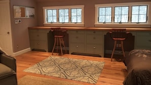 Une cuisine compacte avec deux tabourets de bar, un tapis à motifs et un lit dans la chambre.
