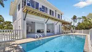 Una casa moderna con piscina, patio cubierto y zona de estar al aire libre.
