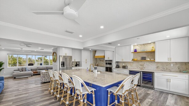 Una cocina amplia con una isla grande, muebles blancos y una pared de acento azul.