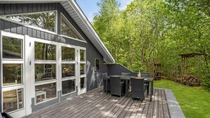 Een terras met buitenmeubilair, een pergola en een houten omheining.