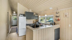 A compact kitchen with wooden walls, a built-in stove, and a refrigerator. - Amazing home in Rødby with sauna (Rødby)