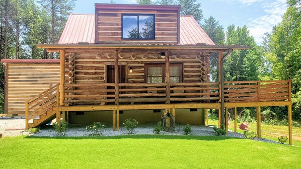 Eine Blockhütte mit einer Holzdiele, einem kleinen Fenster und einer Treppe, die zum Eingang führt.