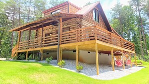 A log cabin with a wooden deck, a sloped roof, and a small porch area. - Three Bears Cabin - Unique Four Bedroom Luxury Cabin with Hot Tub! (Pickens)