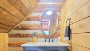 A wooden cabin bathroom with a wooden ceiling, a sink with a mirror, and a towel hanging on the wall. - Three Bears Cabin - Unique Four Bedroom Luxury Cabin with Hot Tub! (Pickens)