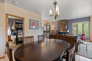 Un comedor con una gran mesa redonda y sillas, una chimenea y vistas al exterior.