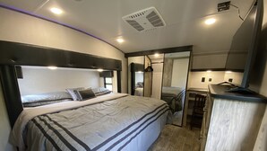A modern bedroom with a large bed, a desk, and a mirror. - 2022 5th Wheel RV, 2BD, Sleeps 6, Kootenai River Views/Access, Picnic Table (Bonners Ferry)