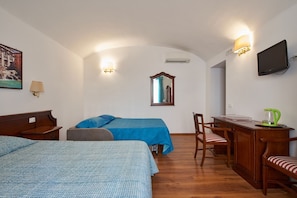 A hotel room with two beds, a desk with a chair, a television, and a mirror.