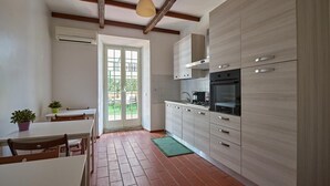 Une cuisine moderne avec des meubles de couleur bois clair, un four encastré et un coin repas comprenant une table et des chaises.