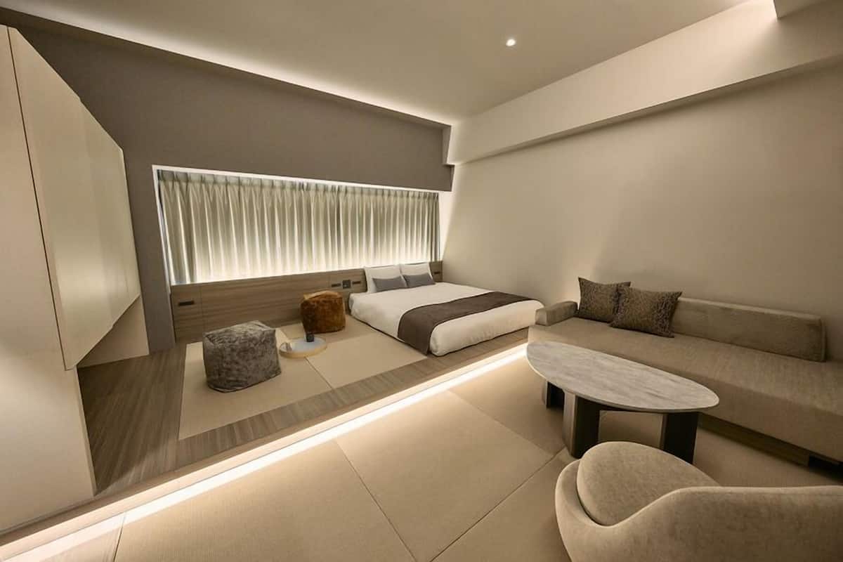 A modern bedroom with a bed, sofa, and a small table.