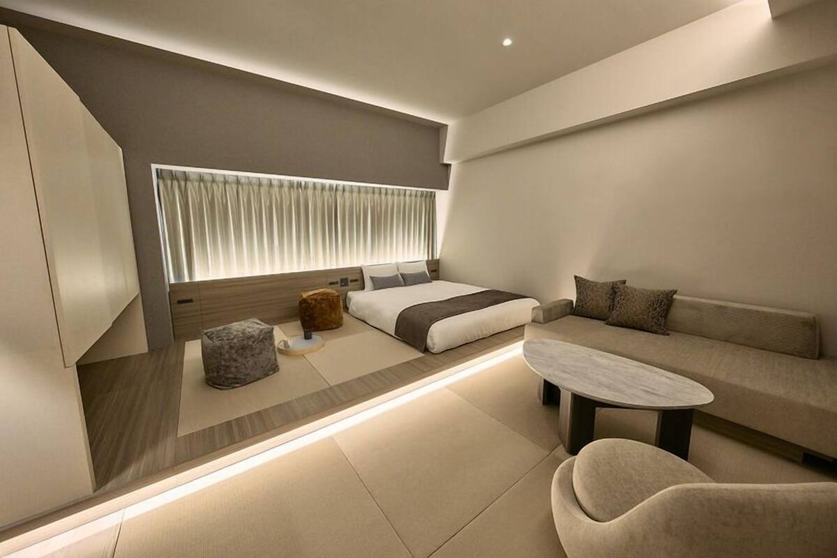 Un dormitorio moderno con cama, sofá y una mesita.