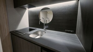 A modern bathroom with a stainless steel sink, a round mirror, and a built-in ventilation system. - fav HIROSHIMA STADIUM (Hiroshima)