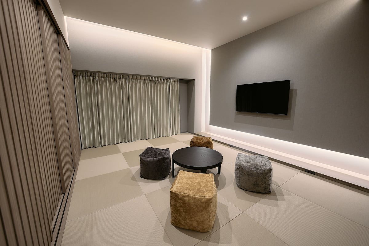 A modern interior with a flat-screen TV mounted on the wall, a round table, and four square ottomans in different colors.